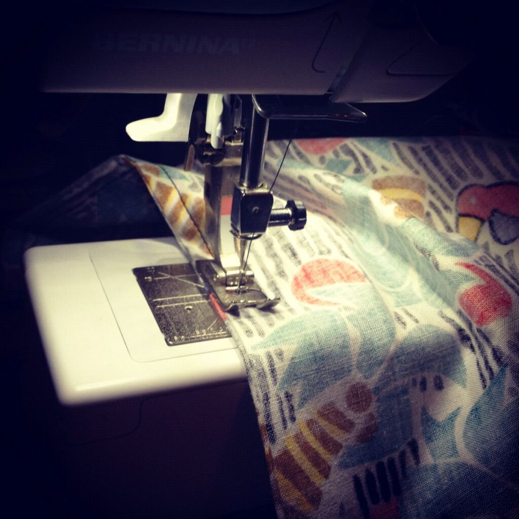 A close up of a sewing machine, showing a French seam in action.