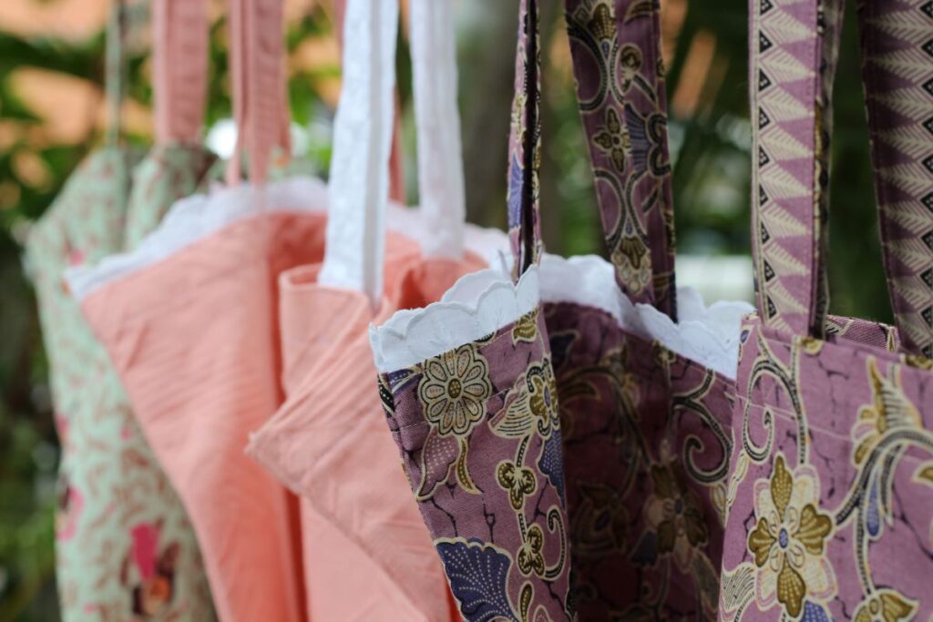 A close up of the six tote bags or reusable grocery bags, hanging in a garden.