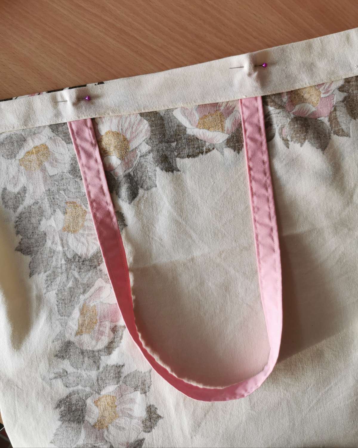 The top hem of a handmade should bag tote, with handle pinned in place ready for sewing.