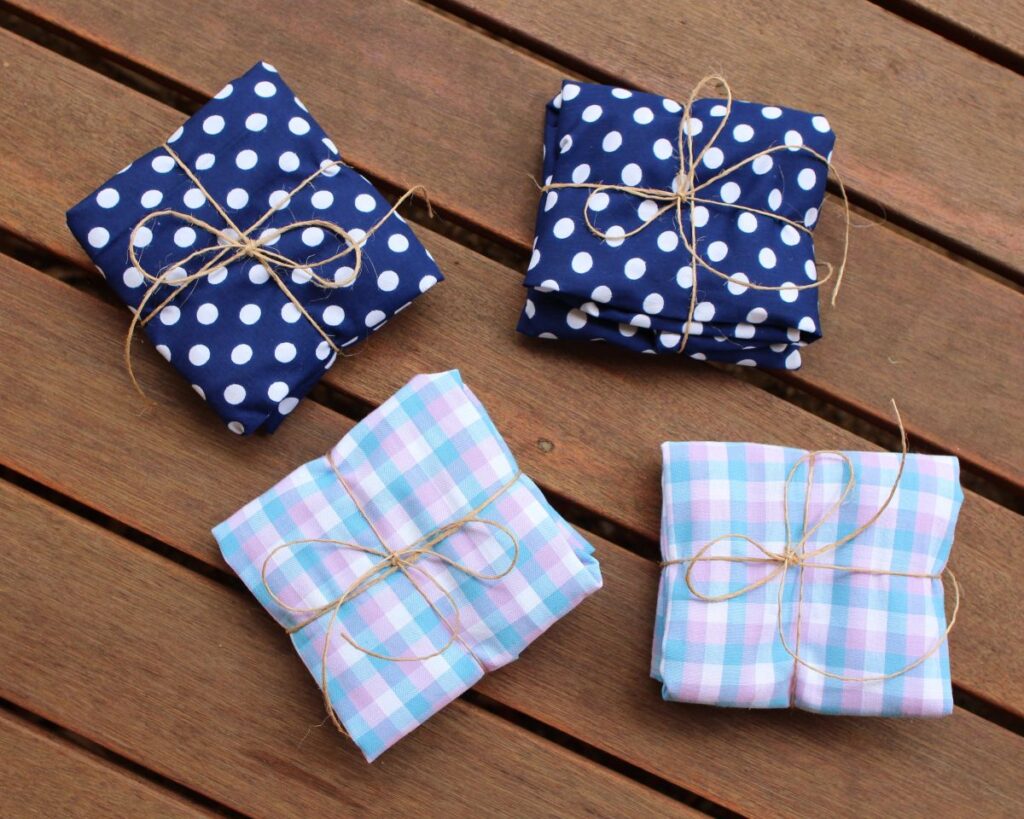 Four shoulder bag totes, wrapped up into squares and tied up with string, ready for gifting.