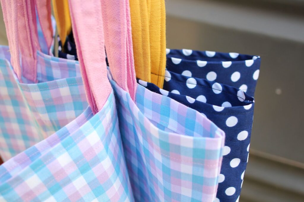 Four brightly coloured bags made from a pattern for a tote bag.