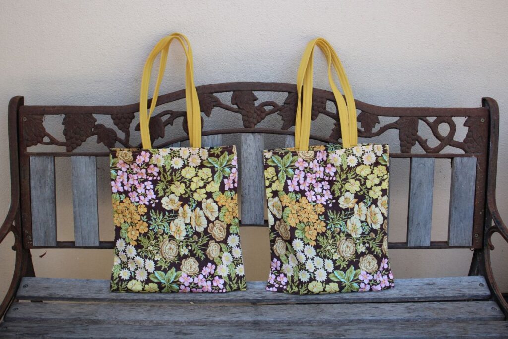 Two shoulder tote bags side by side on a wooden bench.