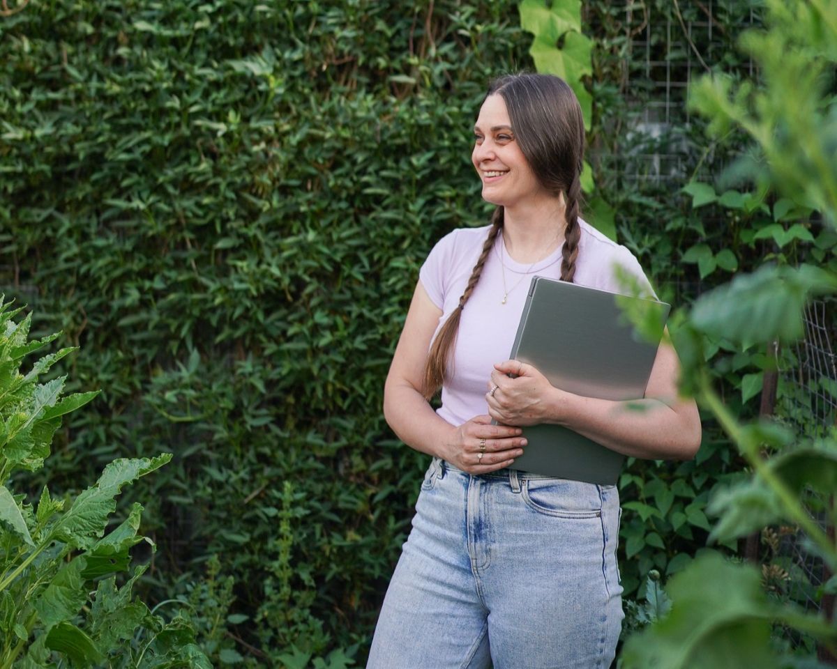 Koren Helbig holding a laptop in front of green wall