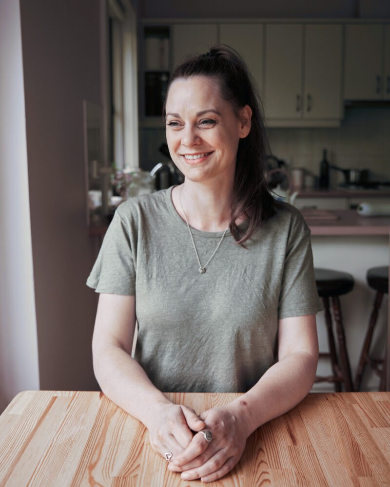Koren Helbig sitting at her kitchen table, smiling