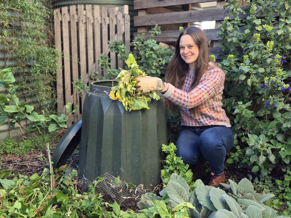 Koren Helbig adding food scraps to a round plastic compost bin