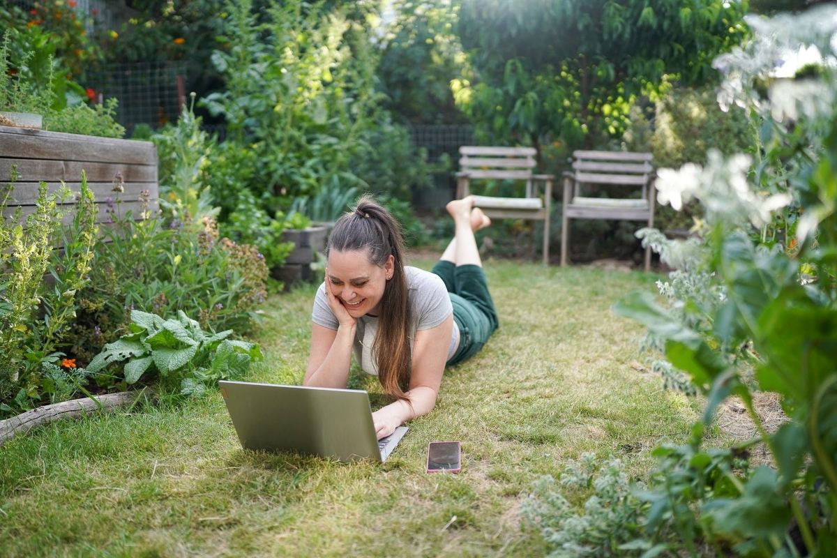 Koren Helbig in her backyard, lying on the grass with a computer