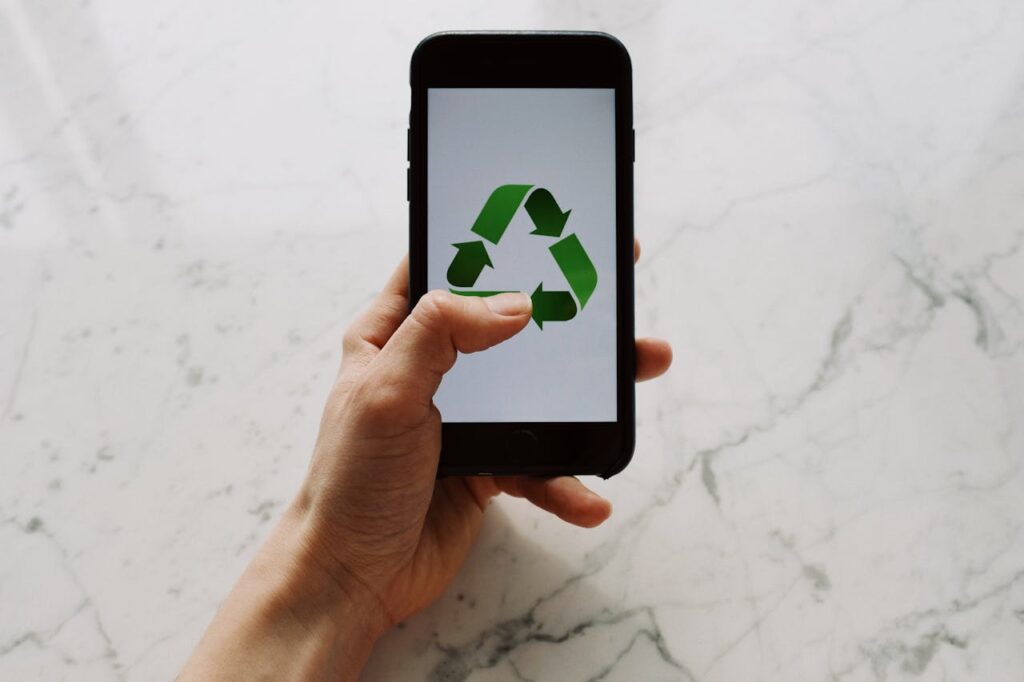 A white hand holding a phone, with a recycle symbol