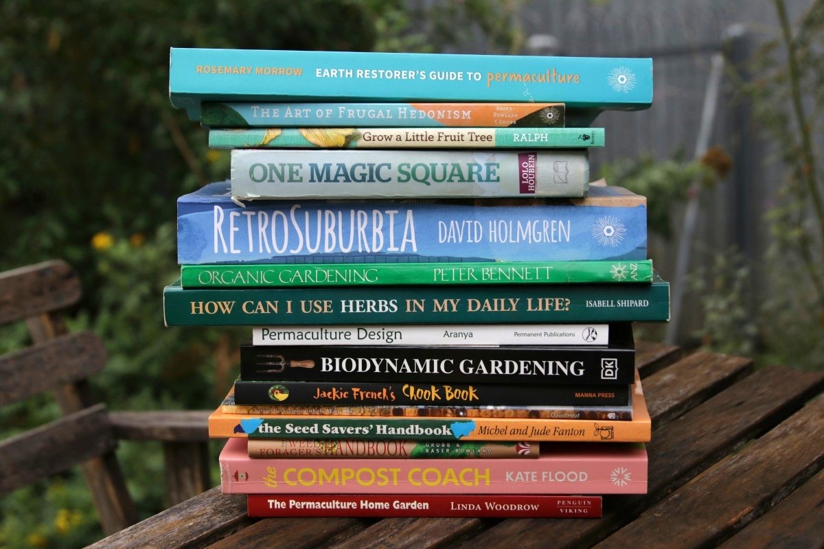 A stack of best permaculture books in an urban garden, atop of wooden outdoor table.